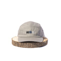 Grey BORA cap with embroidered front logo, front view on a wooden display stand