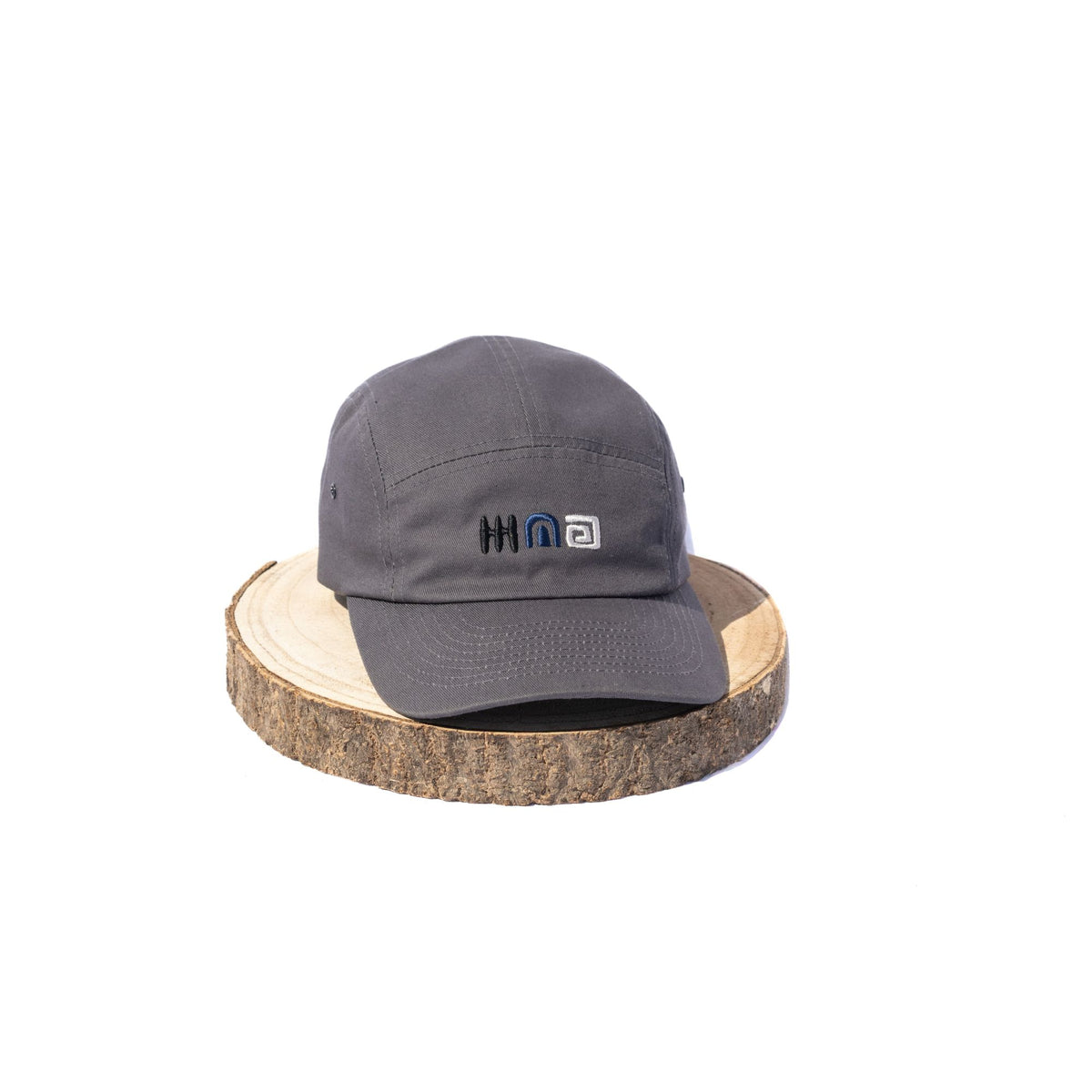 Black BORA cap with embroidered front logo, front view on a wooden display stand